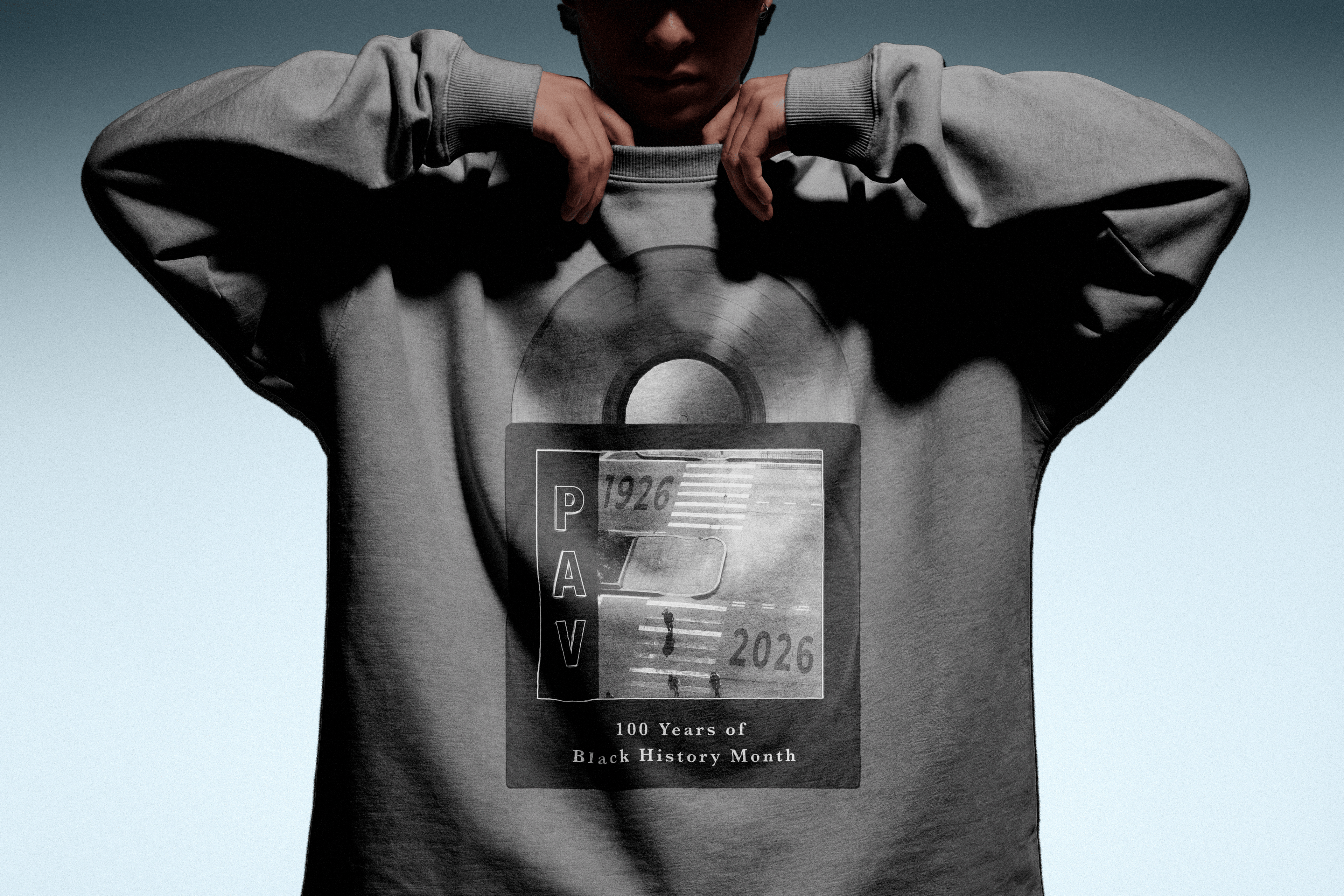 Person wearing a gray 100 year of black history month sweatshirt a gradient background